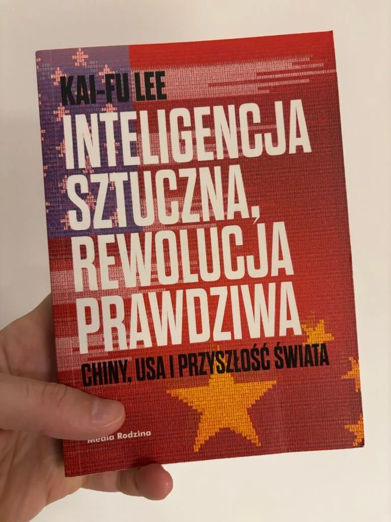 Dłoń trzymająca książkę Kai-Fu Lee „Inteligencja sztuczna, rewolucja prawdziwa”